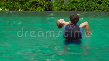 快乐的父子在游泳池里玩耍。 父亲把儿子扔进水里，让他在掉进水里之前翻筋斗